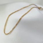 Gold chain necklace on a white fabric background