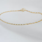 Gold chain bracelet on a light gray background