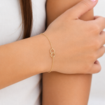 Gold bracelet on a person's wrist with a plain background