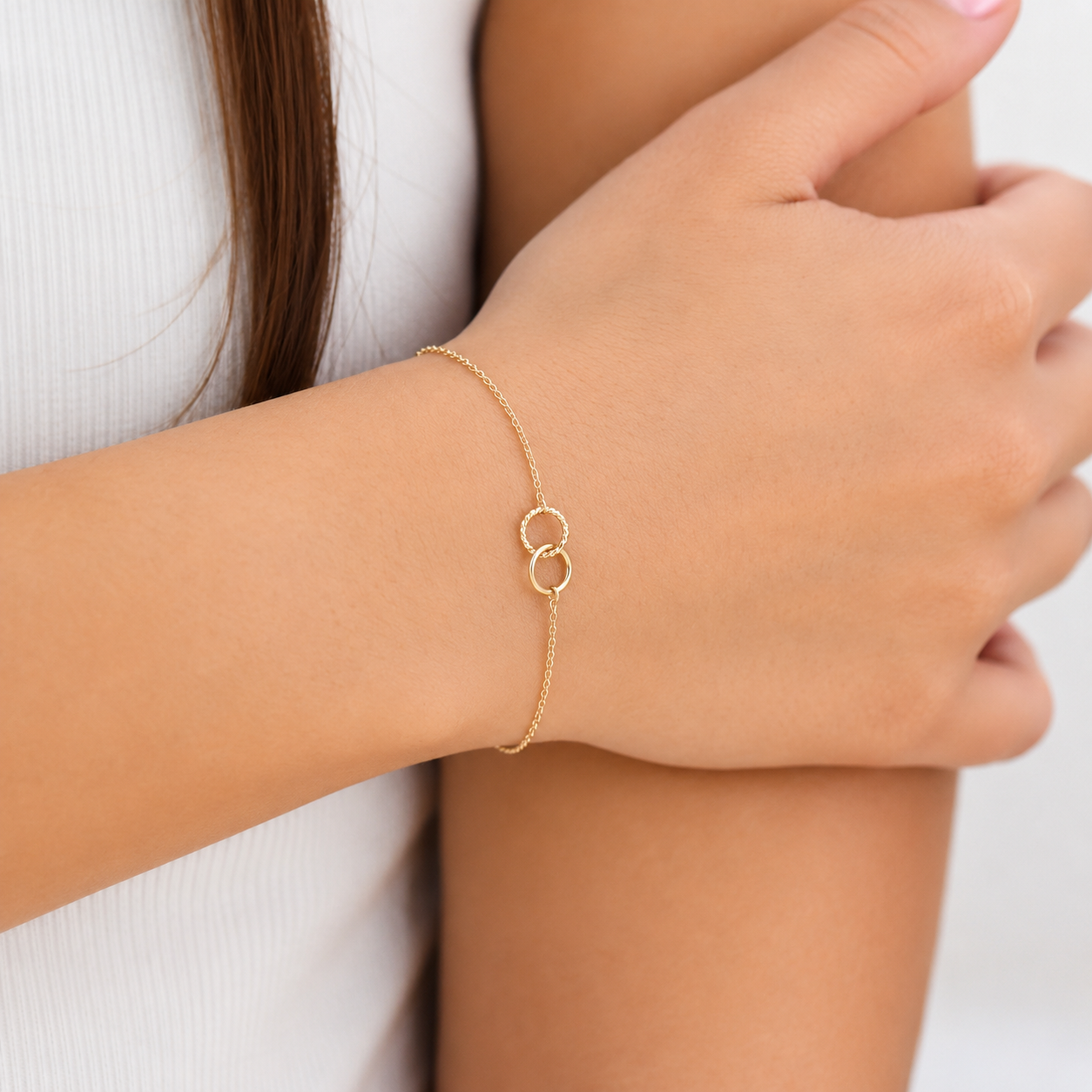 Gold bracelet on a person's wrist with a plain background