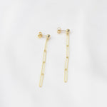 Gold earrings on a light gray background