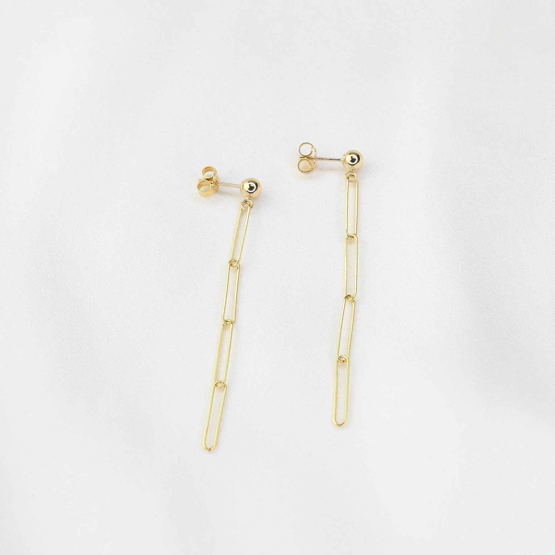 Gold earrings on a light gray background