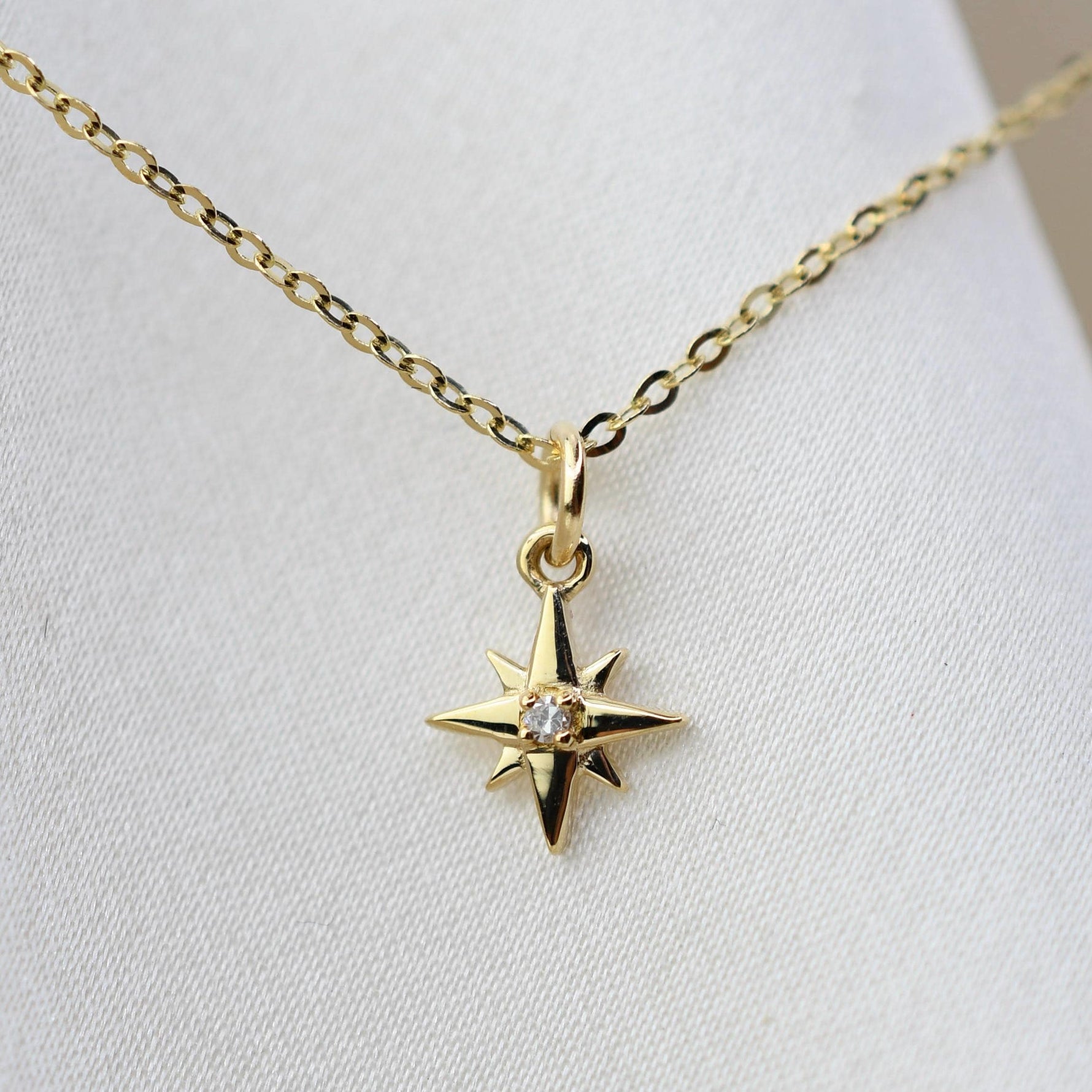 Gold necklace with a star-shaped pendant on a white background