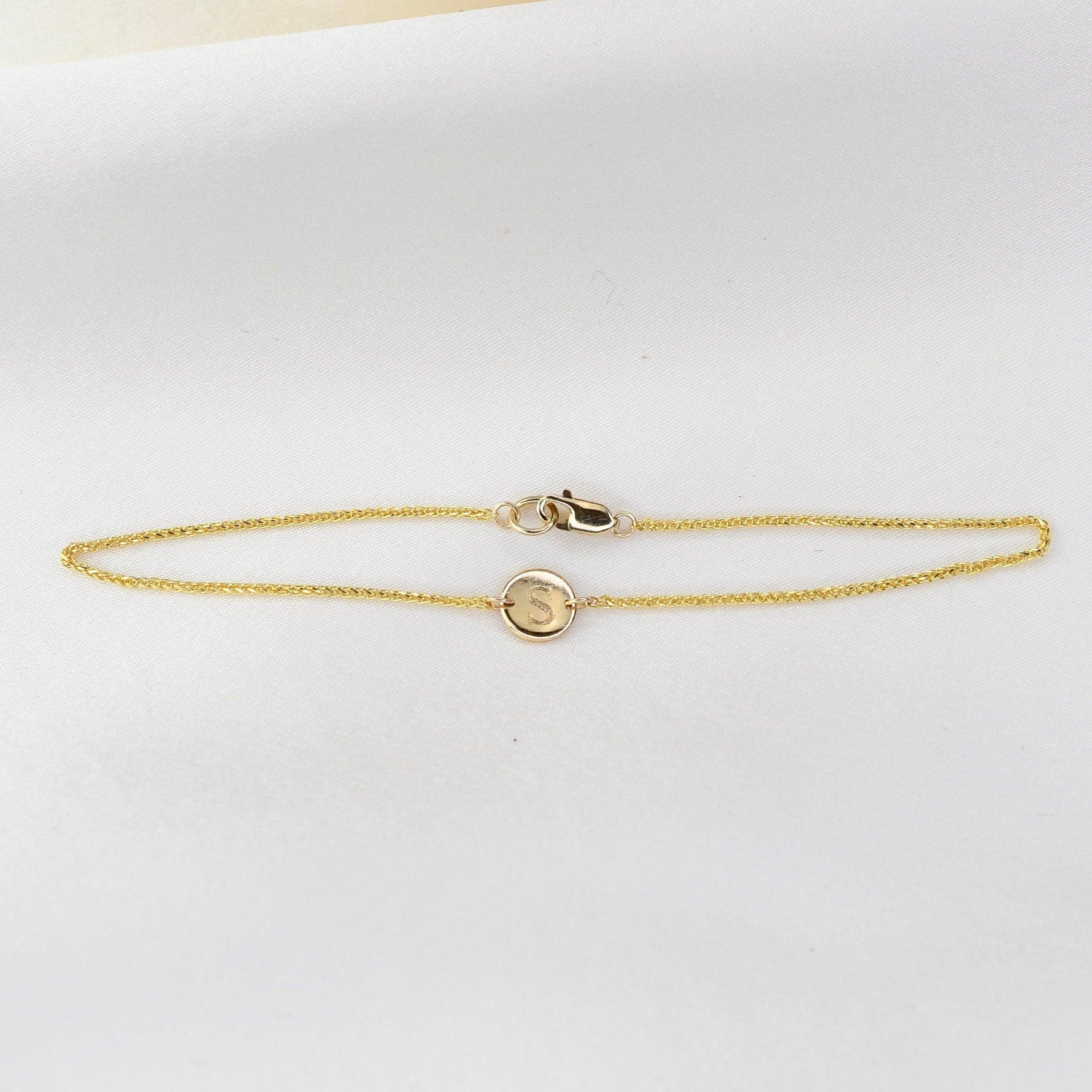 14K gold initial bracelet by Sash Jewelry featuring a tiny personalized letter charm on a delicate chain.