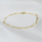 Gold chain bracelet on a light gray background