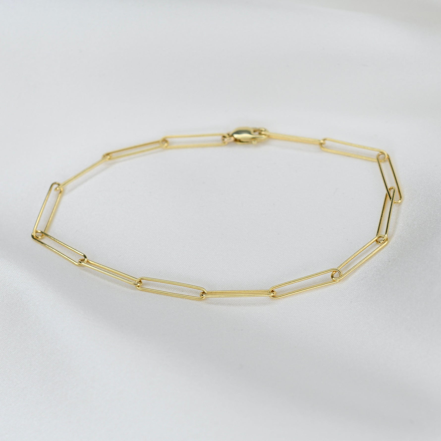 Gold chain bracelet on a light gray background