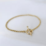 Gold bracelet with a toggle clasp on a white background