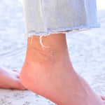 Delicate solid gold heart charm anklet worn on ankle
