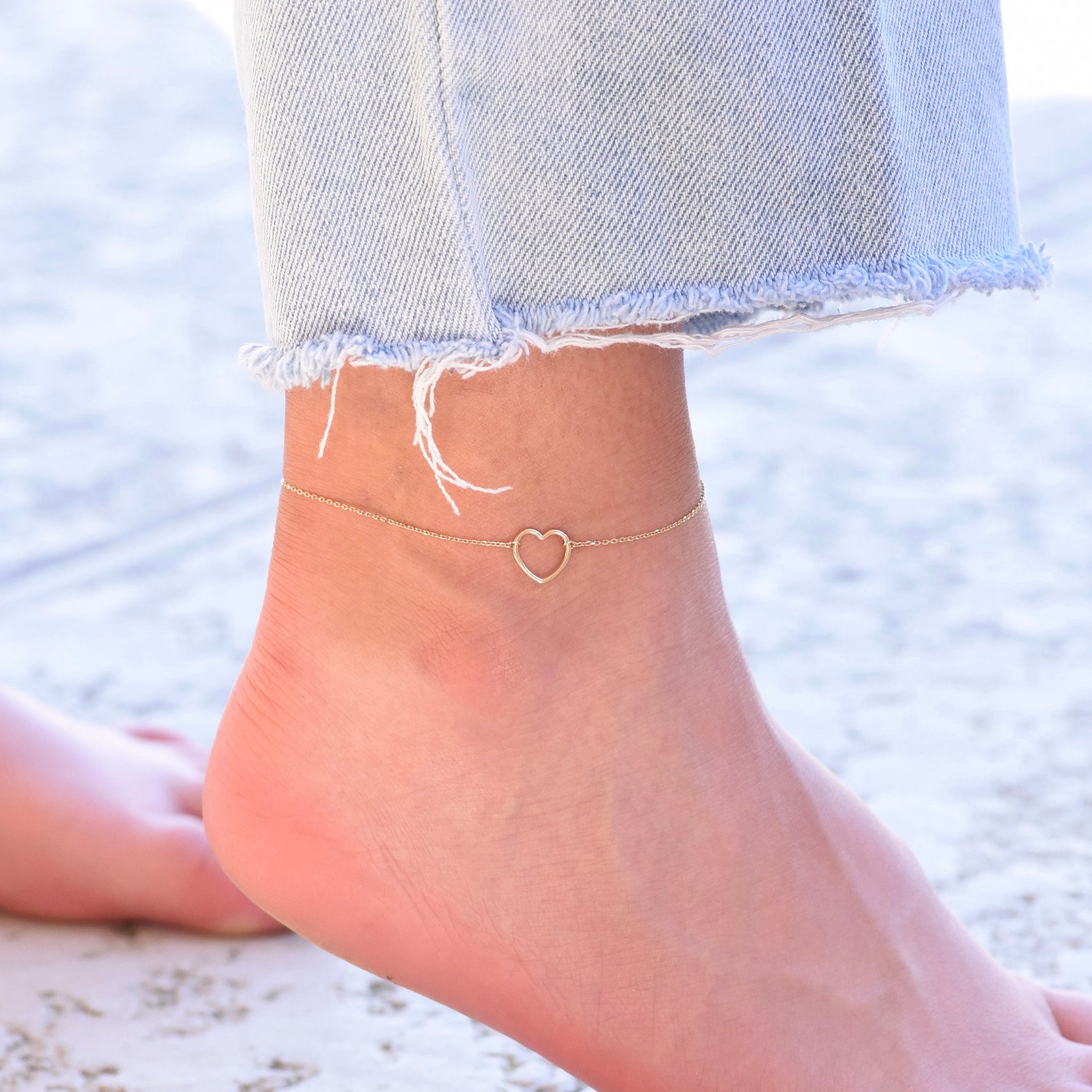 Delicate solid gold heart charm anklet worn on ankle