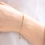 Gold bracelet on a person's wrist against a light background