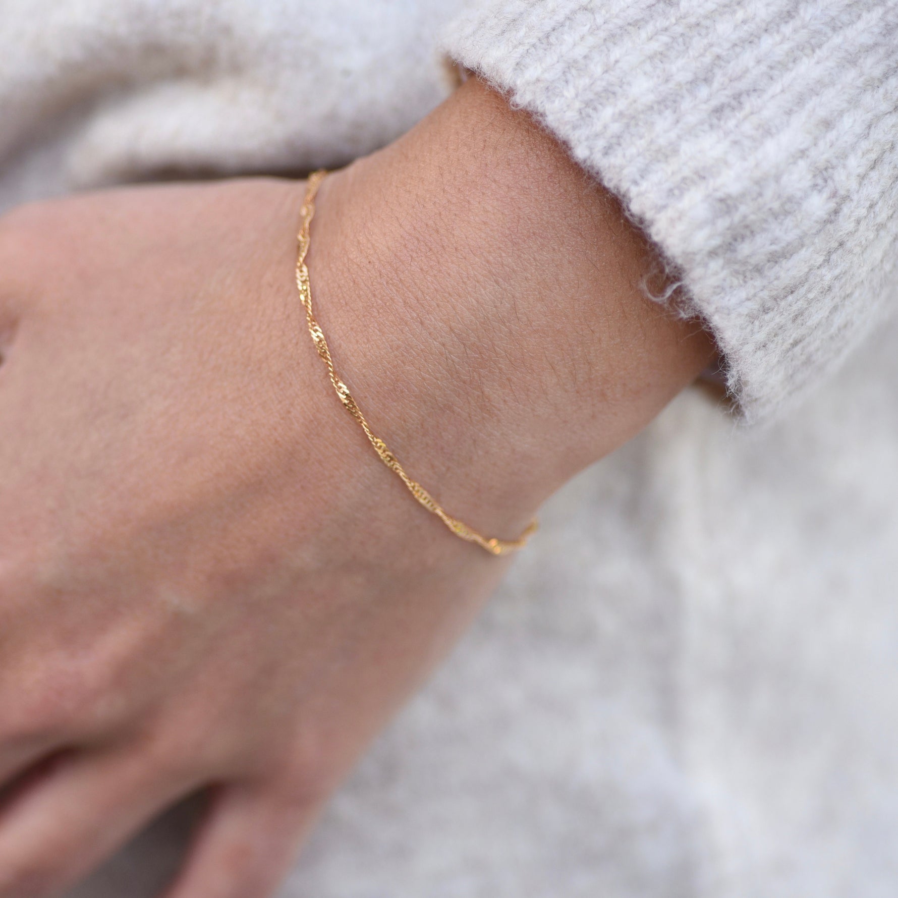 Gold bracelet on a wrist with a blurred background