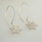 Silver snowflake earrings on a light gray background