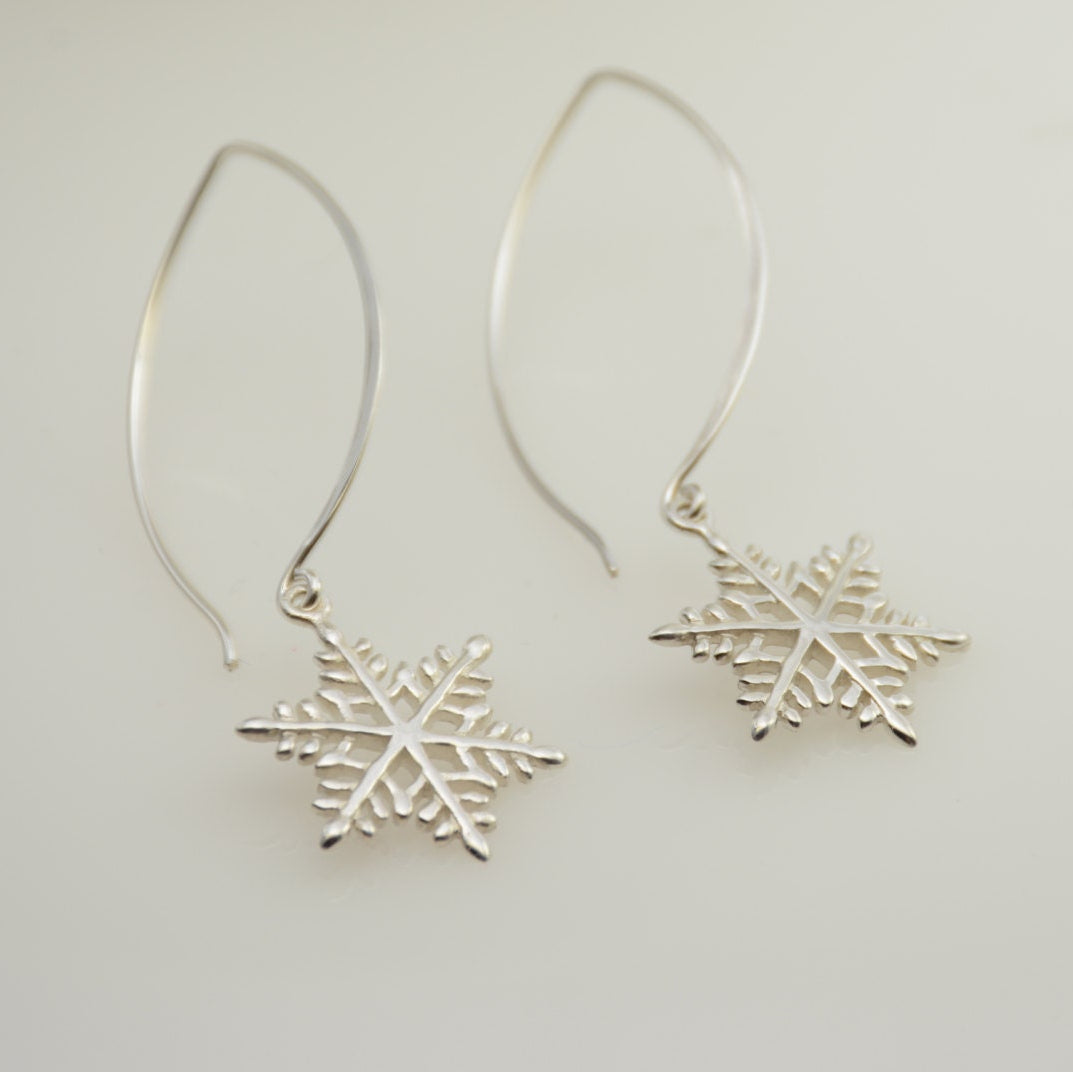 Silver snowflake earrings on a light gray background