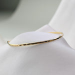 Gold bracelet on a white fabric background