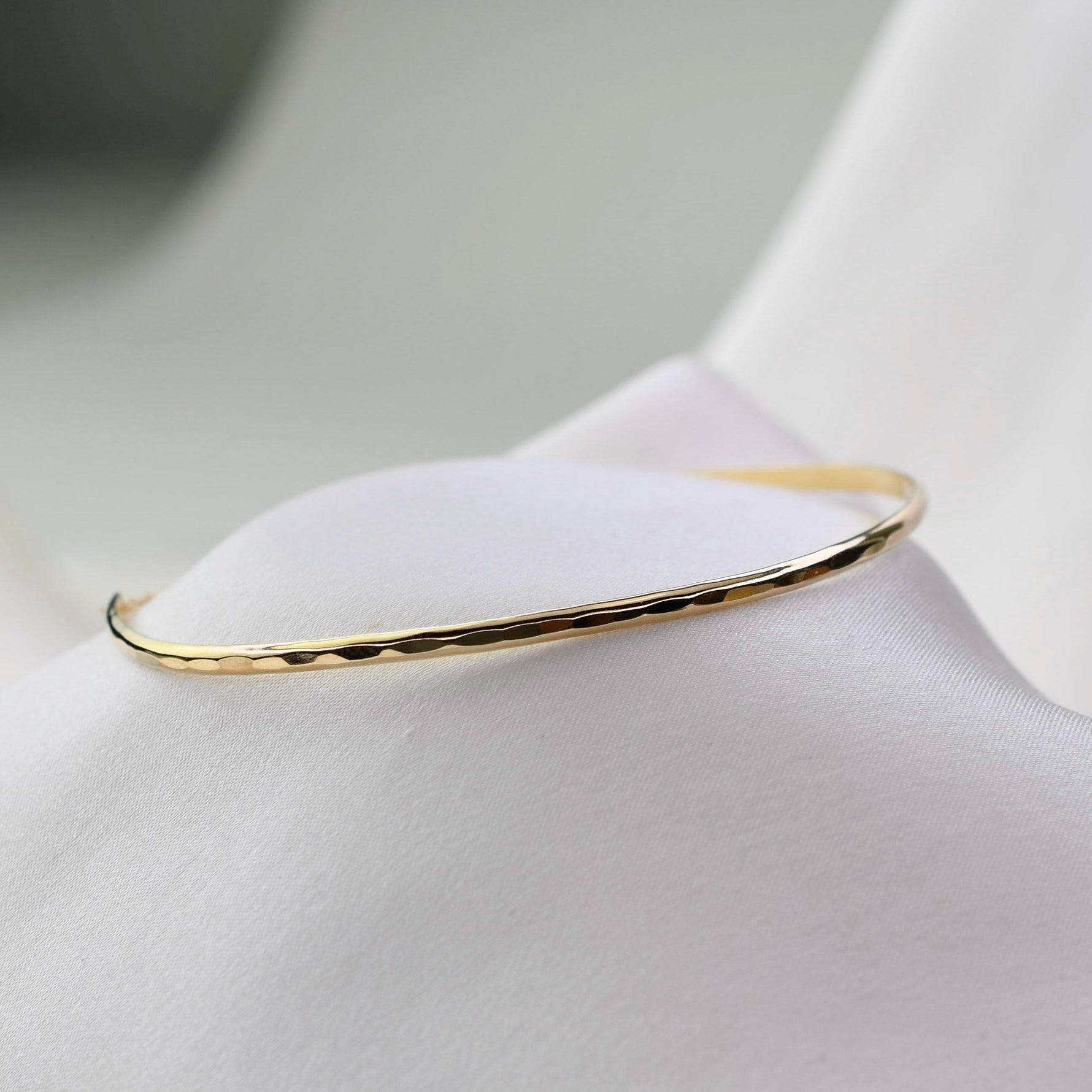 Gold bracelet on a white fabric background