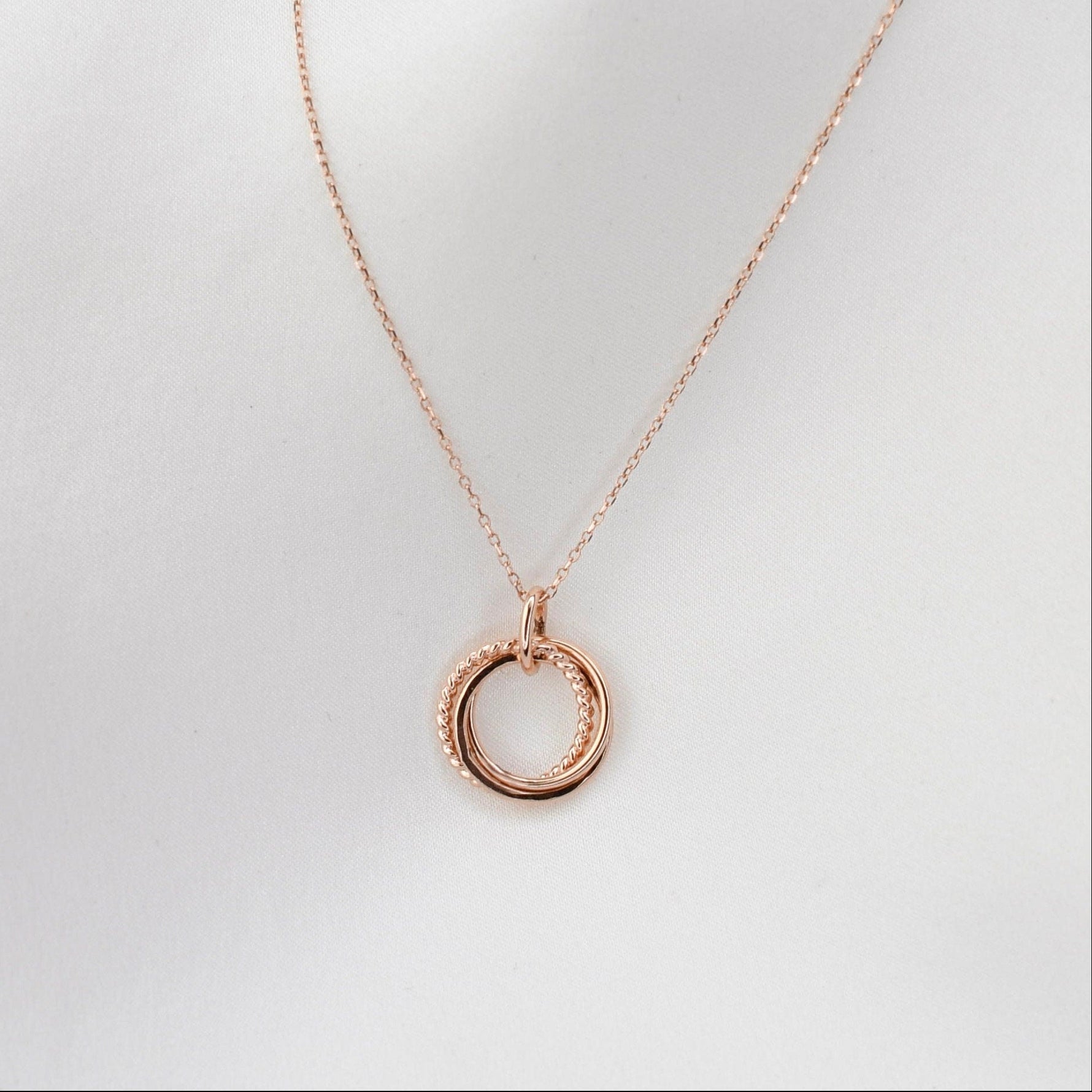 Rose gold necklace with a circular pendant on a light gray background
