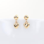 Gold heart-shaped earrings on a light gray background