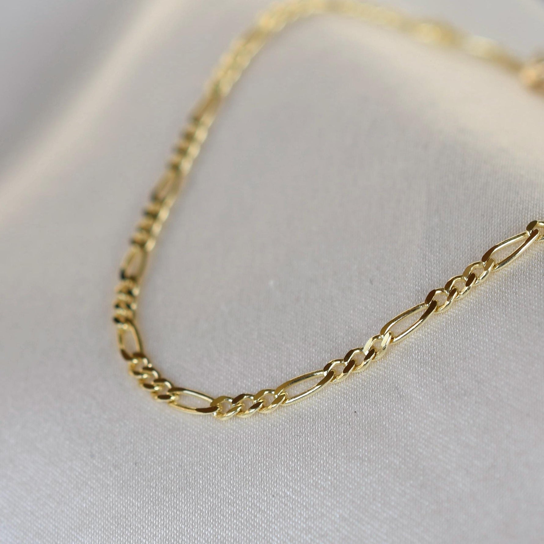 Gold chain necklace on a light gray background