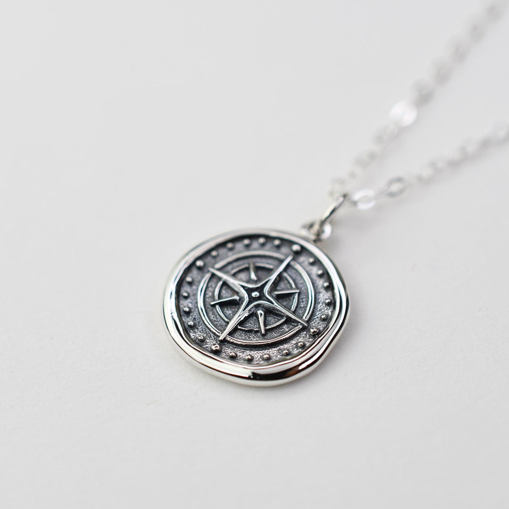 Sash Jewelry compass necklace with wax seal pendant, featuring intricate travel-themed design, on a chain for stylish wear.