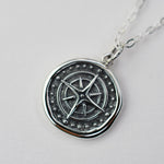 Silver pendant with star design on a light gray background