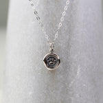 Silver necklace with a round pendant on a light gray background
