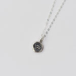 Silver necklace with a paw print pendant on a light gray background