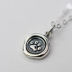Silver pendant with paw print design on a light gray background