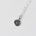 Silver necklace with a circular pendant on a light gray background