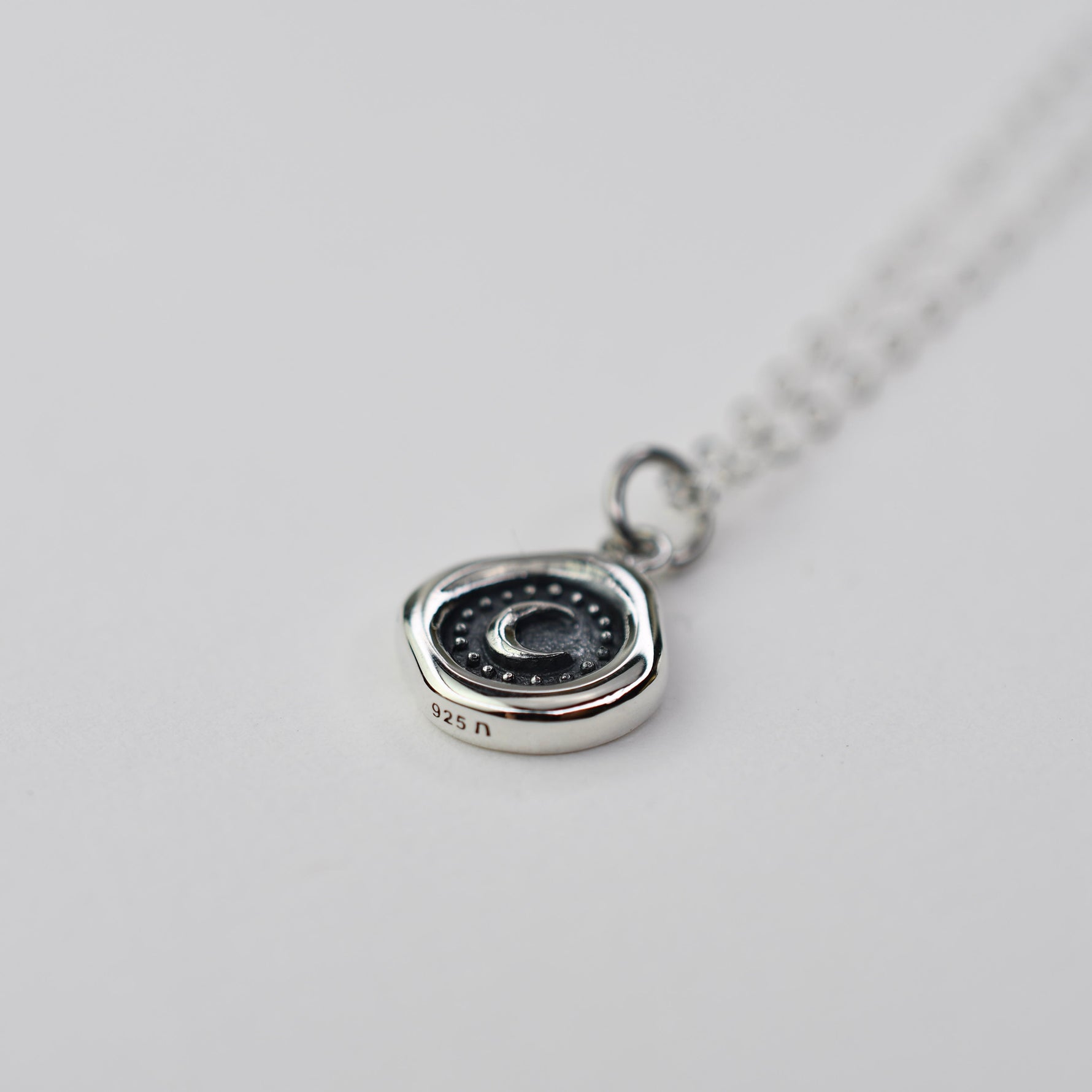Silver necklace with a pendant on a light gray background