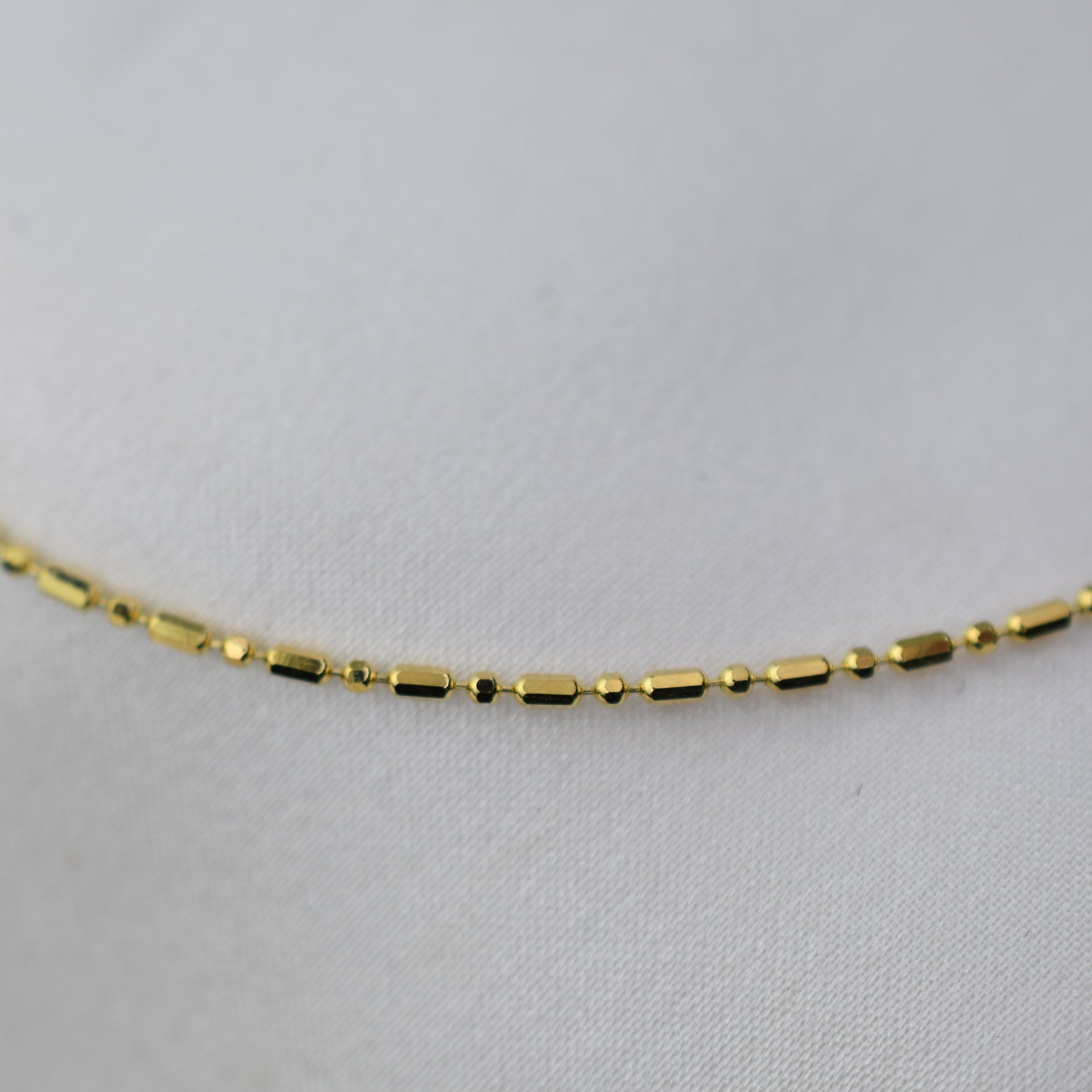 Gold necklace on a light gray background