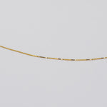 A delicate gold chain necklace shown against a plain light gray background.