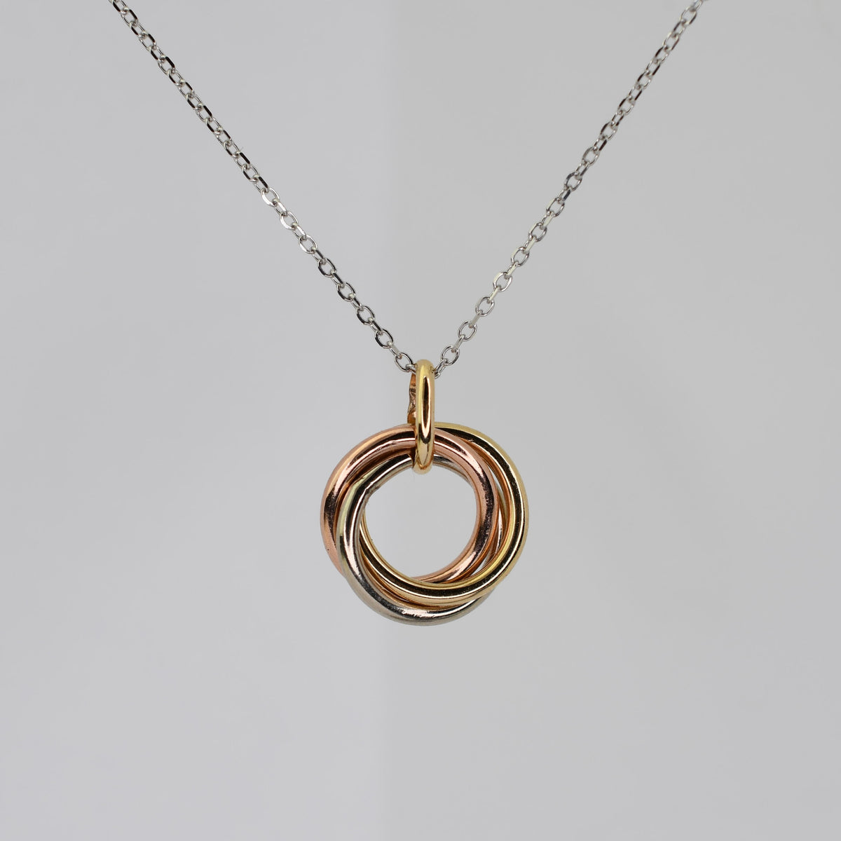 14K solid gold three interlocking rings necklace in yellow, white, and rose gold with an adjustable 16–18" chain.