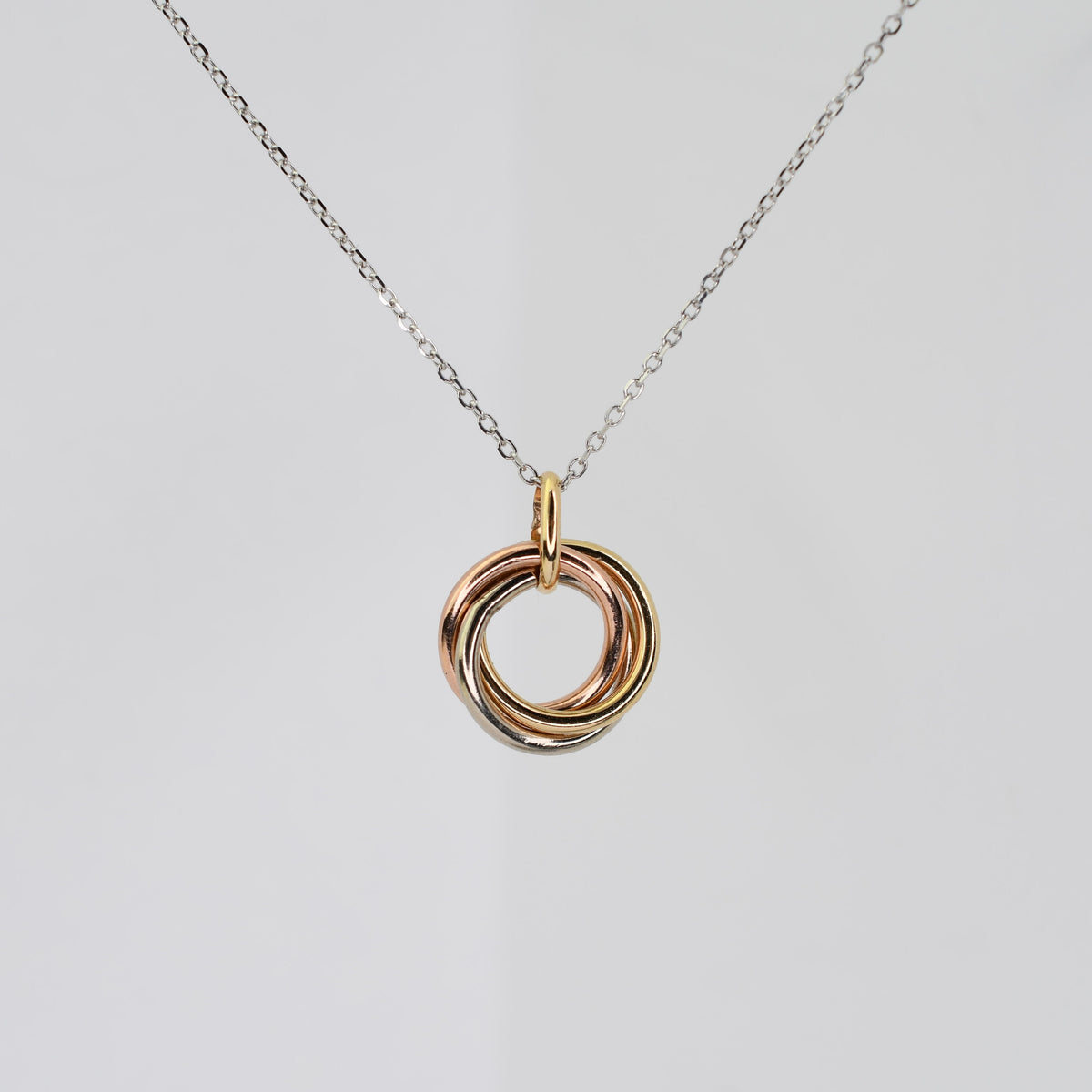 14K solid gold tri-color necklace with three interlocking yellow, white, and rose gold rings on a delicate adjustable chain.