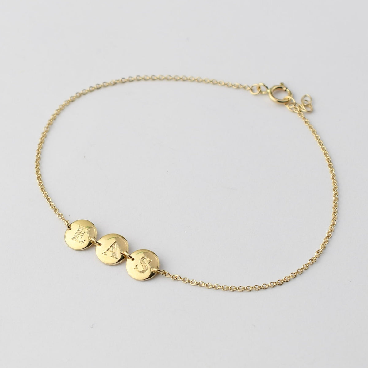 Personalized 14K solid gold initial disc bracelet by Sash Jewelry with engraved initial charm and delicate chain.
