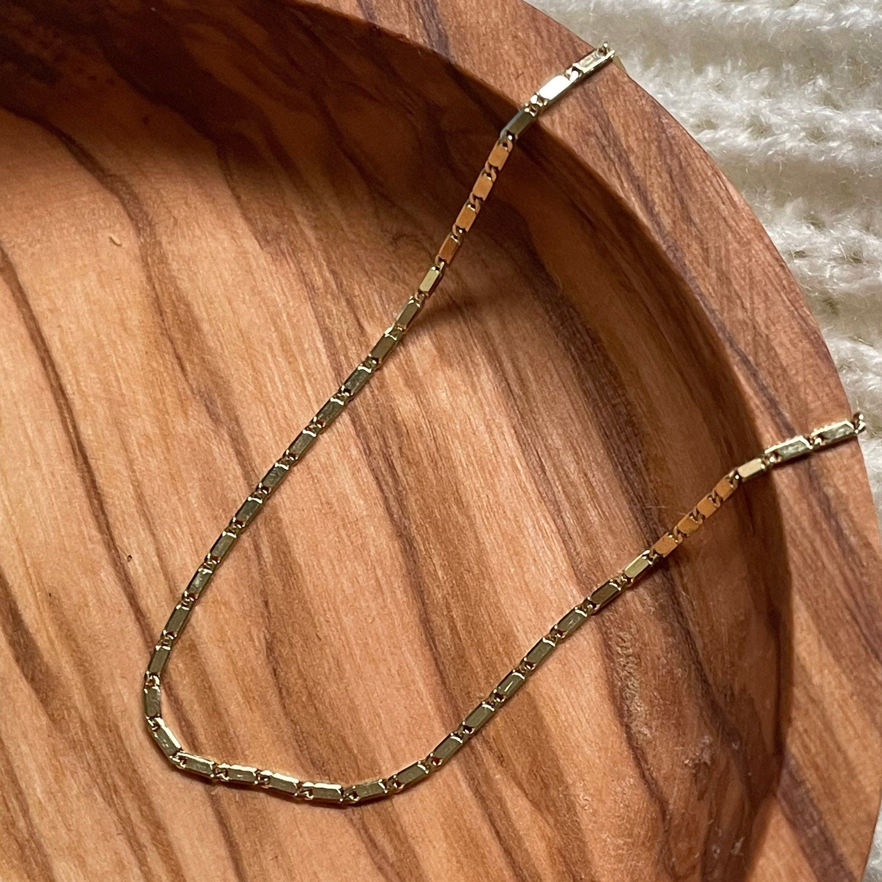 Gold chain necklace on a wooden surface
