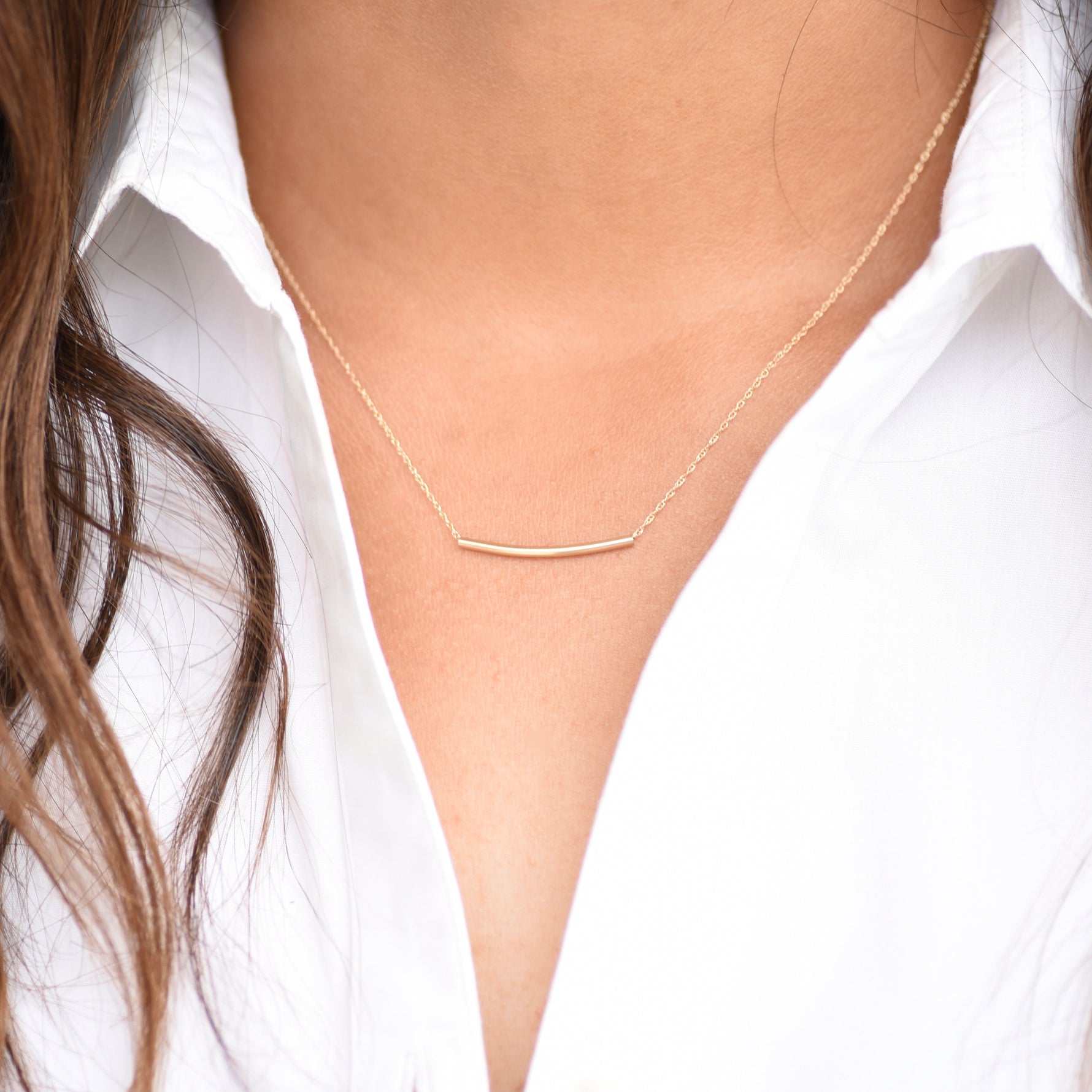Gold necklace worn by a person with a white shirt