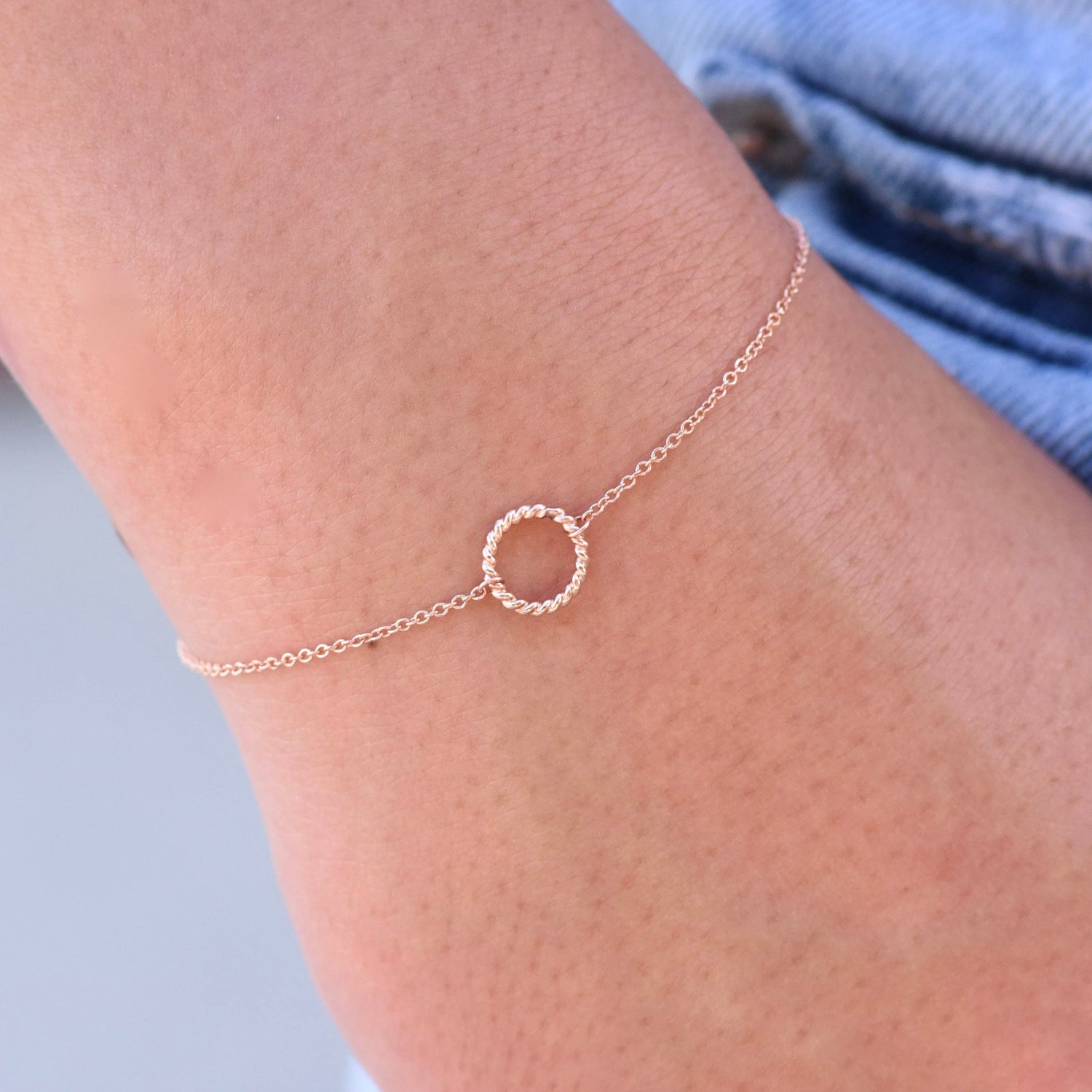 Rose gold anklet with a small circle charm on a person's ankle against a light background