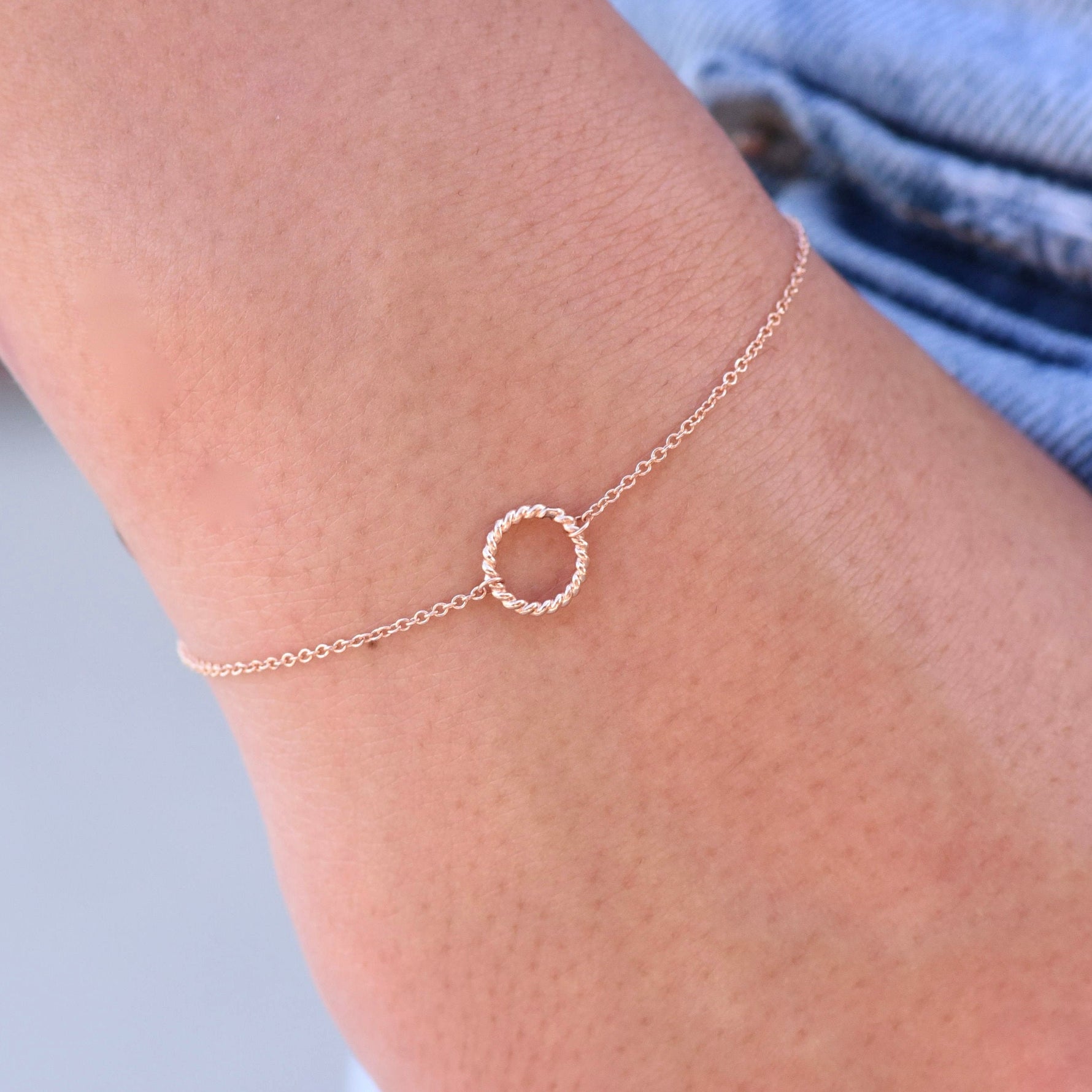 Rose gold anklet with a small circle charm on a person's ankle against a light background
