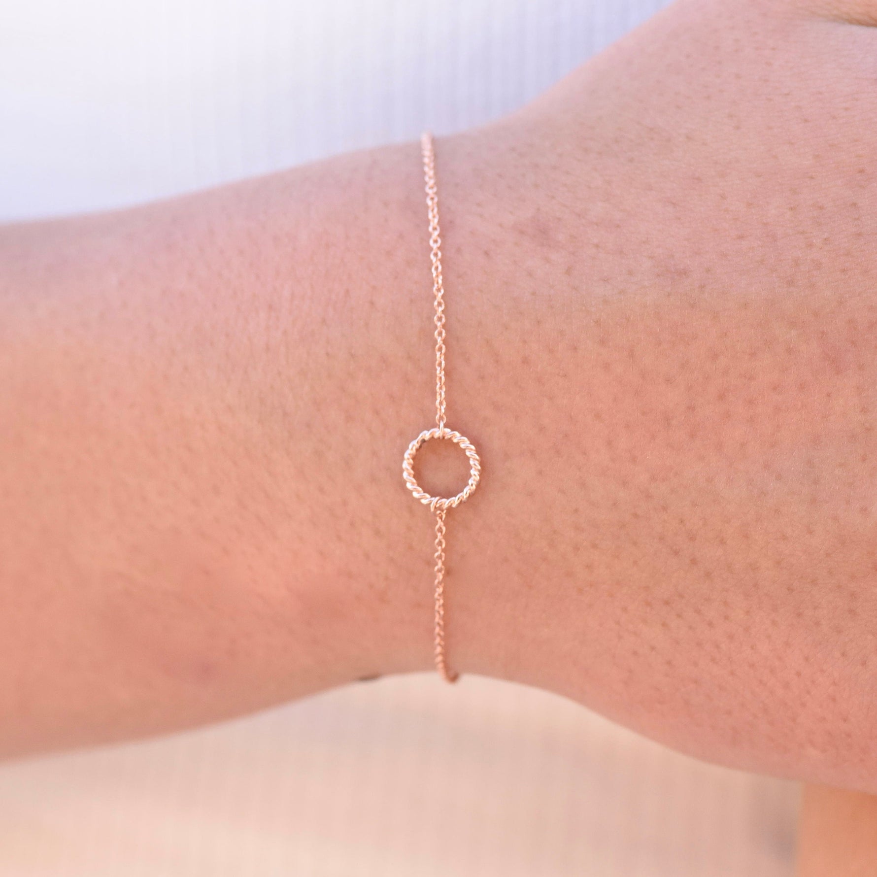 Rose gold bracelet on a wrist with a plain background