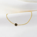 14K gold tiny initial bracelet with personalized letter charm from Sash Jewelry, featuring a delicate solid gold design.