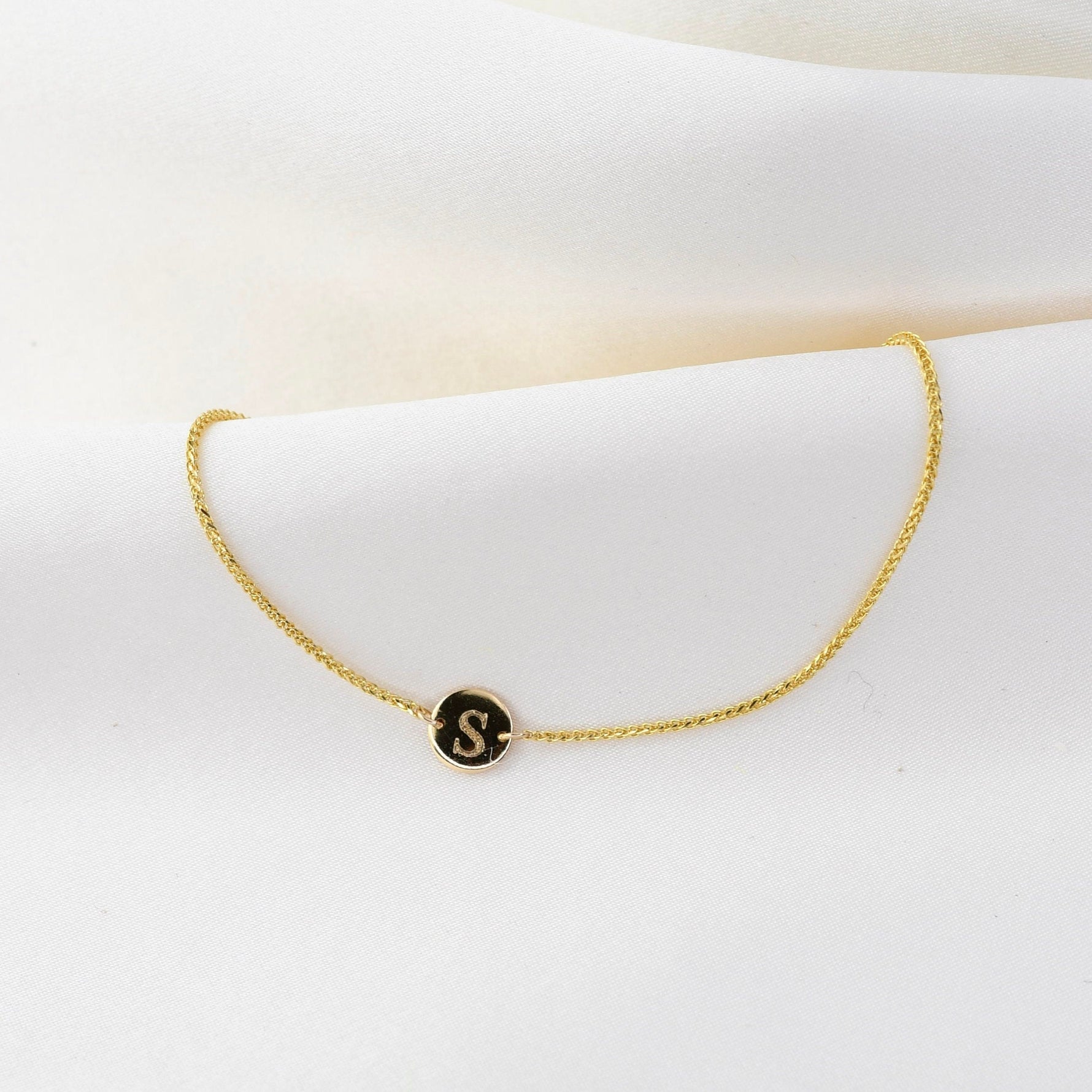 14K gold tiny initial bracelet with personalized letter charm from Sash Jewelry, featuring a delicate solid gold design.