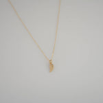 Gold necklace with a small pendant on a light gray background