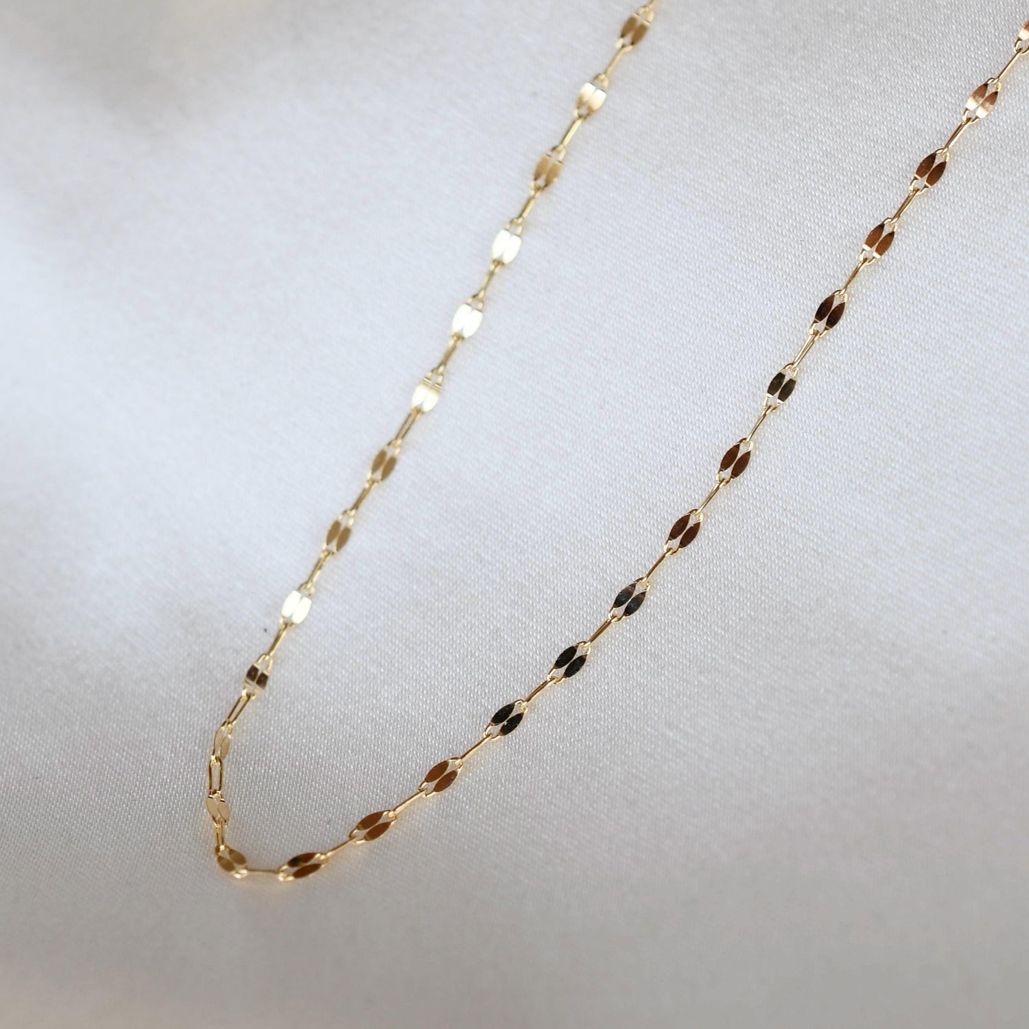 14K gold delicate necklace from Sash Jewelry featuring a fine chain and elegant design, shown close-up against a neutral background.