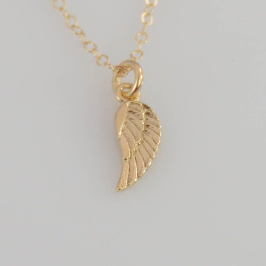 Gold angel wing necklace on a light gray background