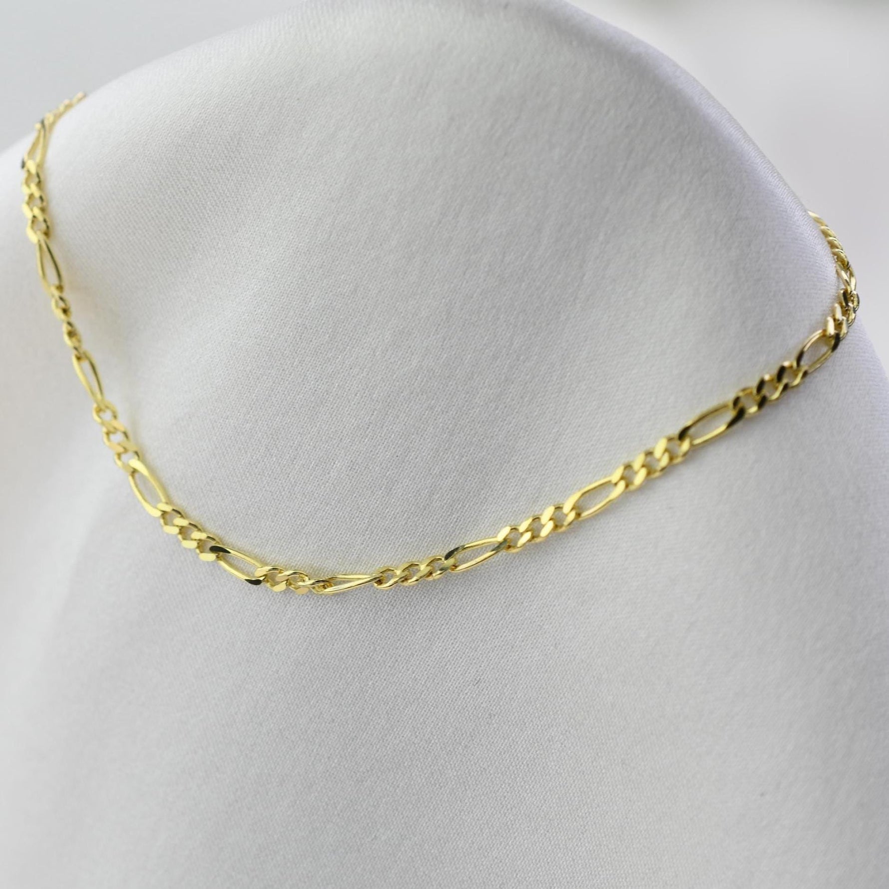 Gold chain necklace on a mannequin bust with a white background