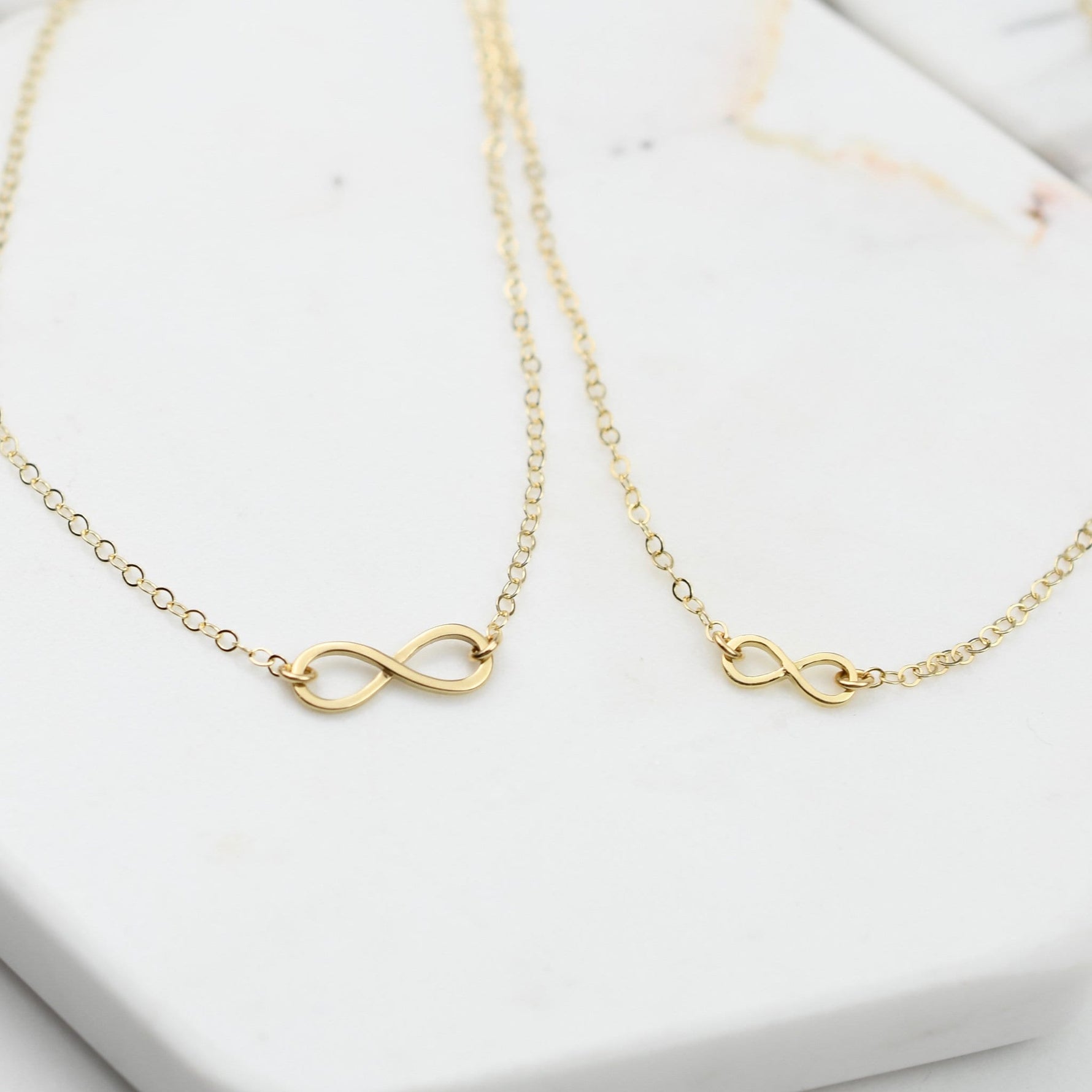 Gold infinity necklace on a white surface