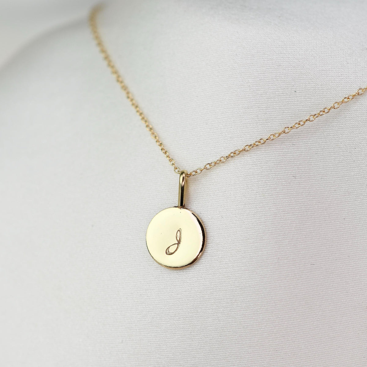 14K gold initial charm necklace with minimalist gold disc pendant, elegant jewelry by Sash Jewelry, close-up of necklace on a white background.