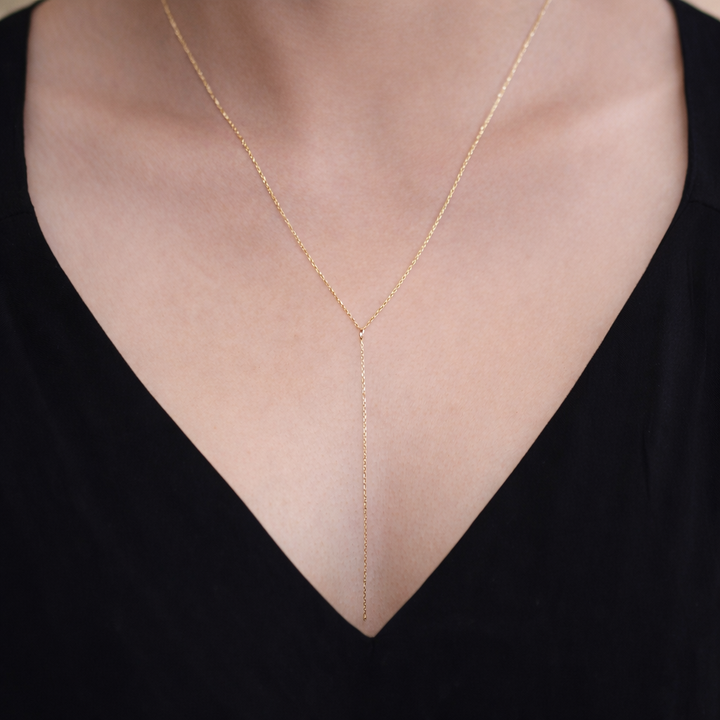 Gold necklace on a person wearing a black top