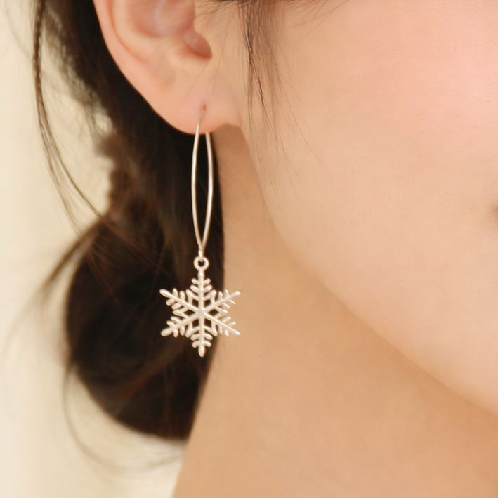 Close-up of a person wearing a snowflake earring with a soft focus on the background