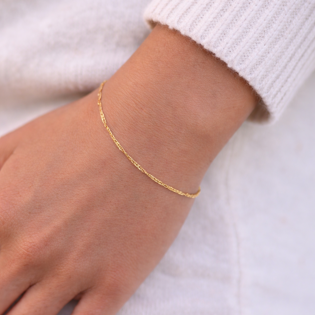 Gold bracelet on a person's wrist against a white background